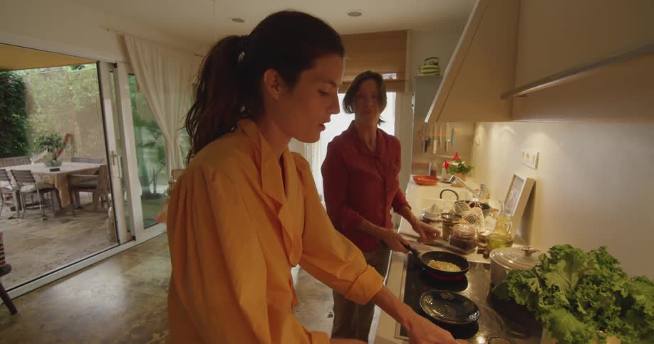 Friends talk while cooking breakfast in kitchen