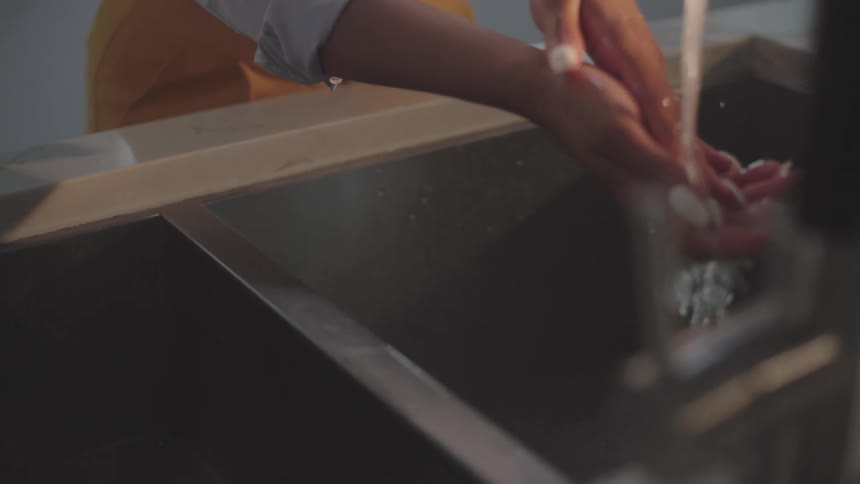 Woman with long white fingernails washing her hands on the kitchen sink