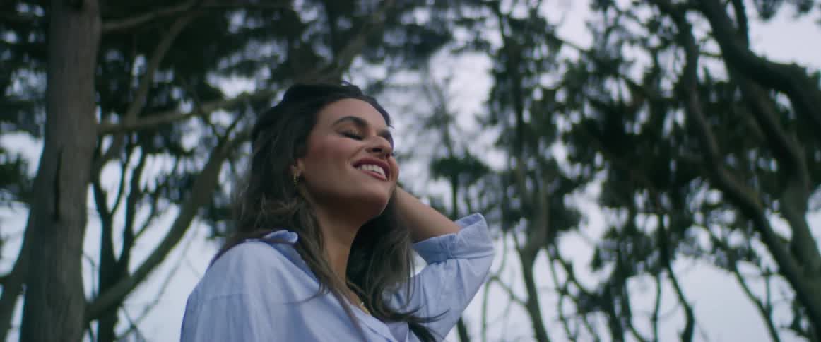 Young beautiful woman stands smiling near to a forest at evening