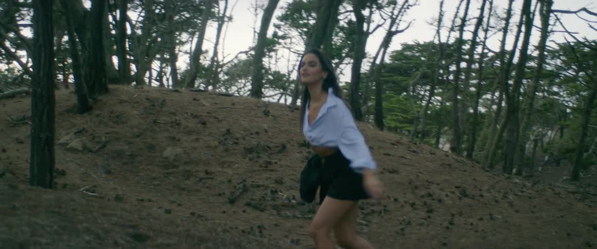 Young woman wearing shorts and a blue shirt waking on a forest at morning