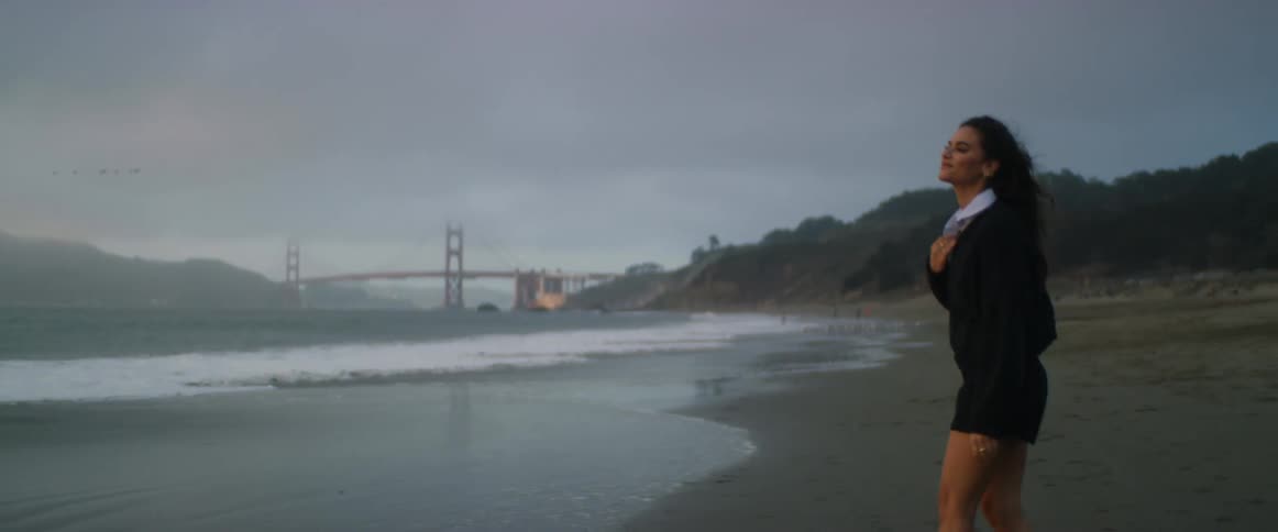A woman walks to the shore on a windy day
