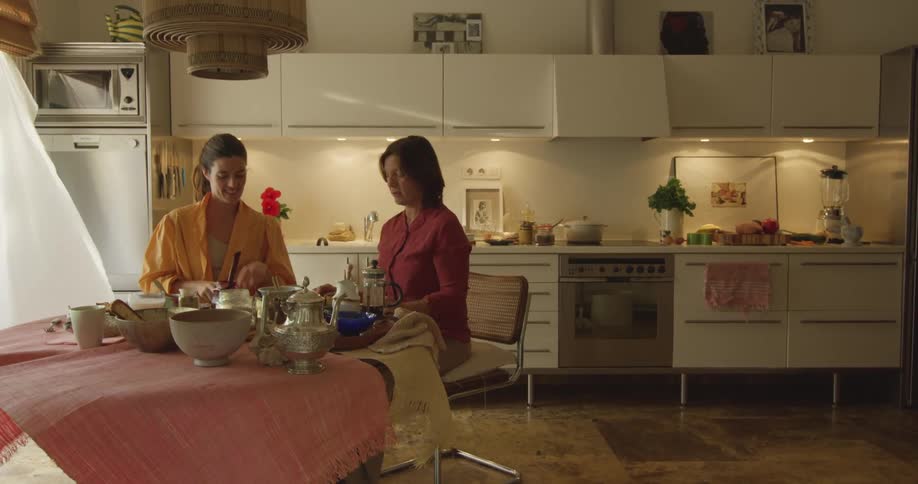 Two women are sitting down at a table eating a meal and talking