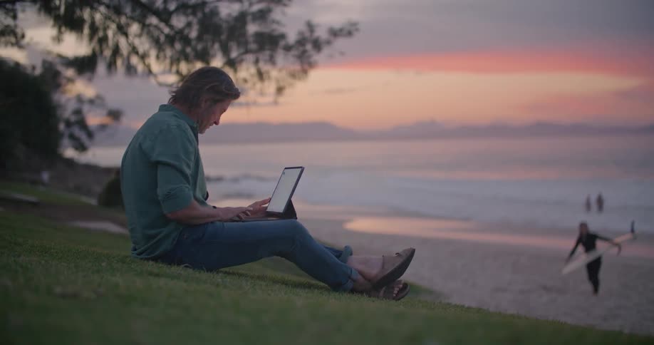 A man typing on a tablet outdoors
