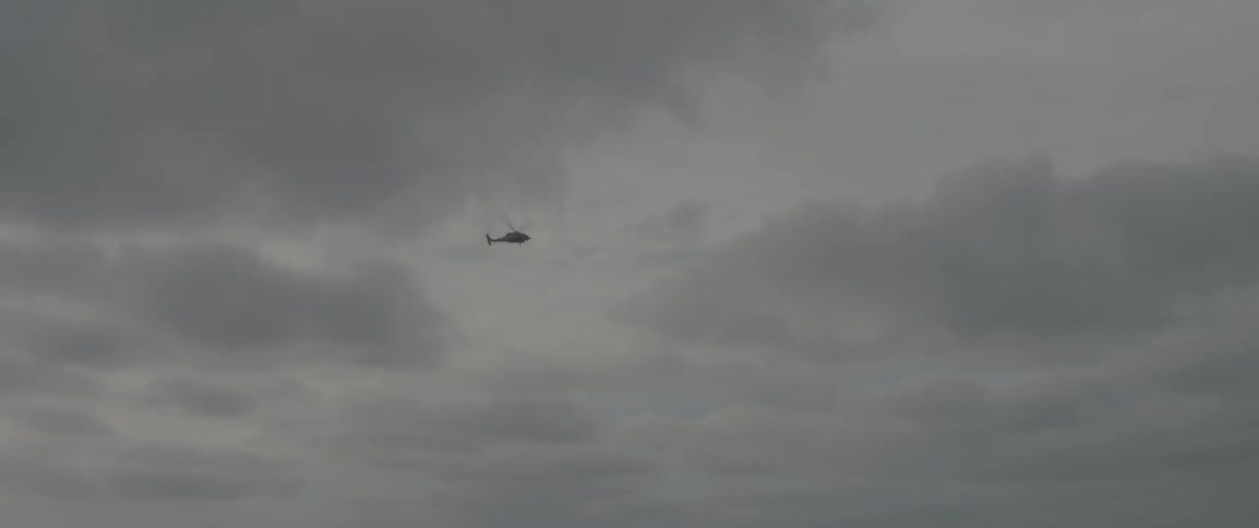 A helicopter is flying in a cloudy sky