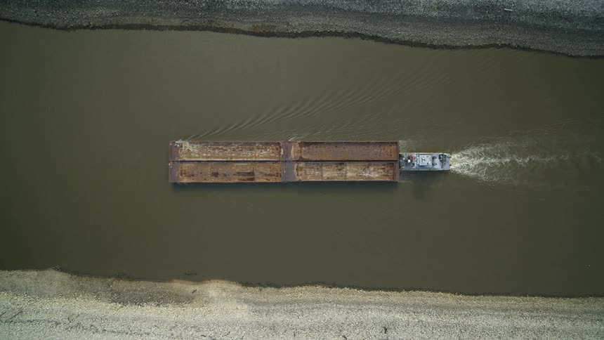 Birds eye view of a towboat pushing four barges upriver