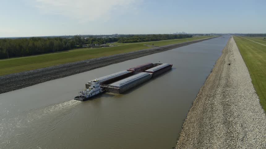 A cargo barge moving down a narrow waterway