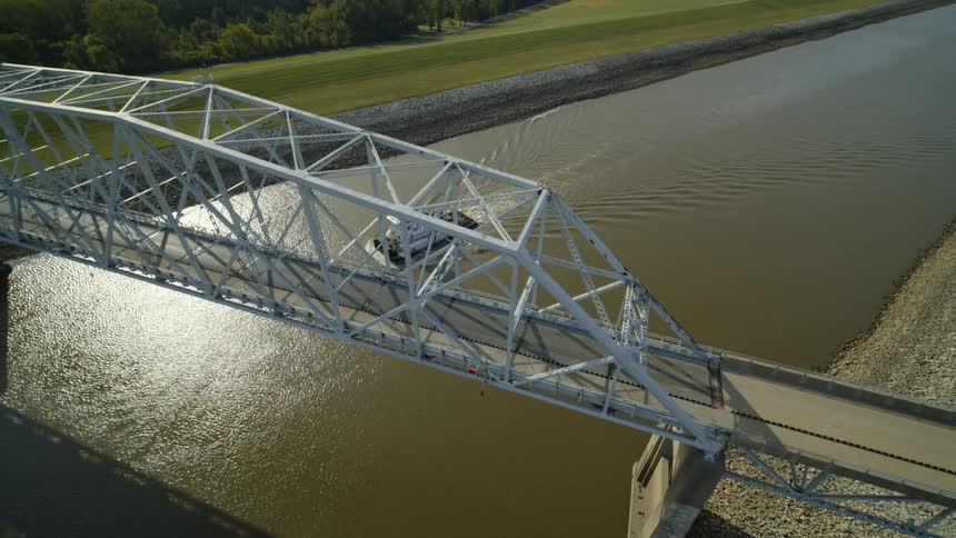 A towboat makes its way under a bridge as the morning sun reflects off the water
