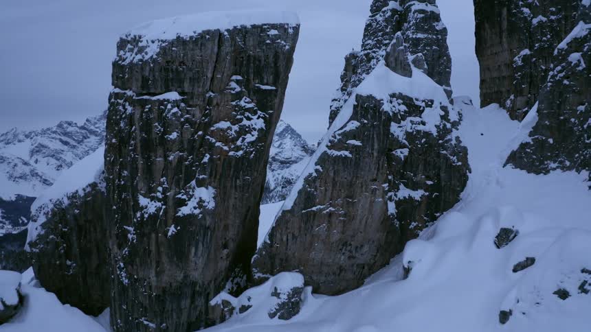 Large rock crags are sticking up out of the snow in the mountain wilderness