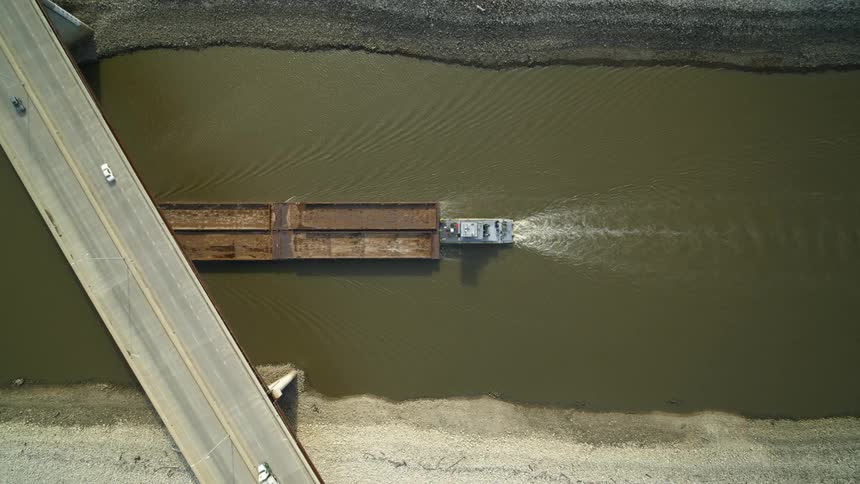 A barge is pushed under a bridge as vehicles drive over