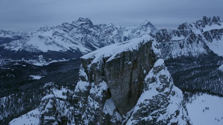 An aerial view of snow capped mountain and trees in the valley