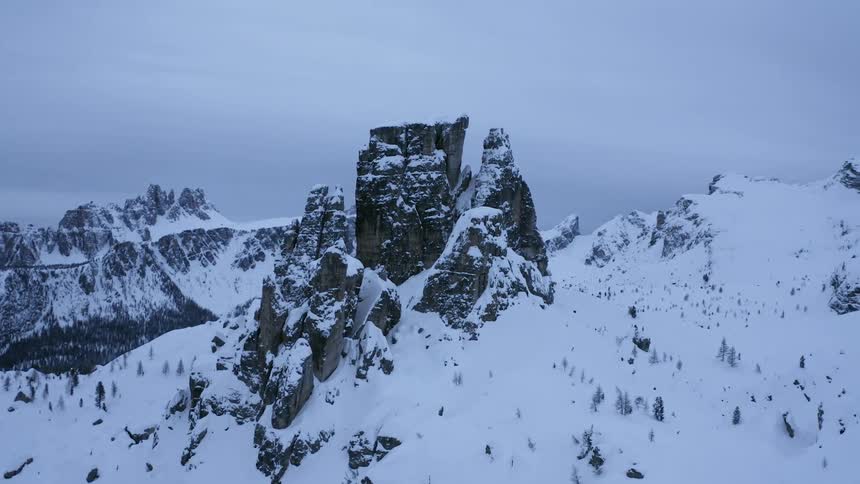 Snow covers forest valley and mountain slopes around tall narrow steep mountains topped with plateau