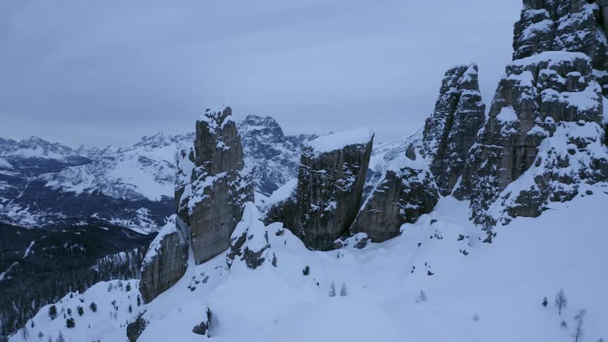 A snow covered mountain range with trees in the valley