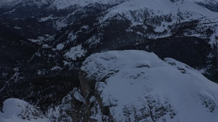 A forest sits at the bottom of the snow covered mountain range