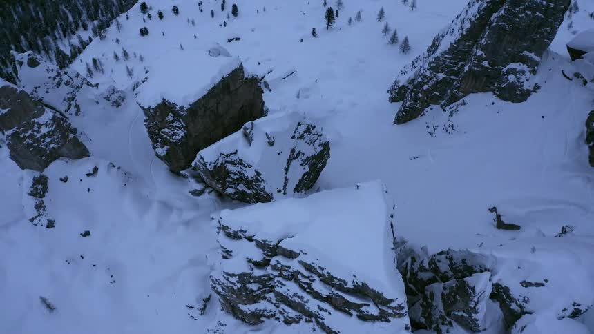 Snow covers mesa and tall rock near forest