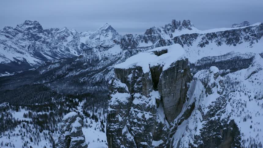 Snow covers flat topped mountain forest valley and mountains in background