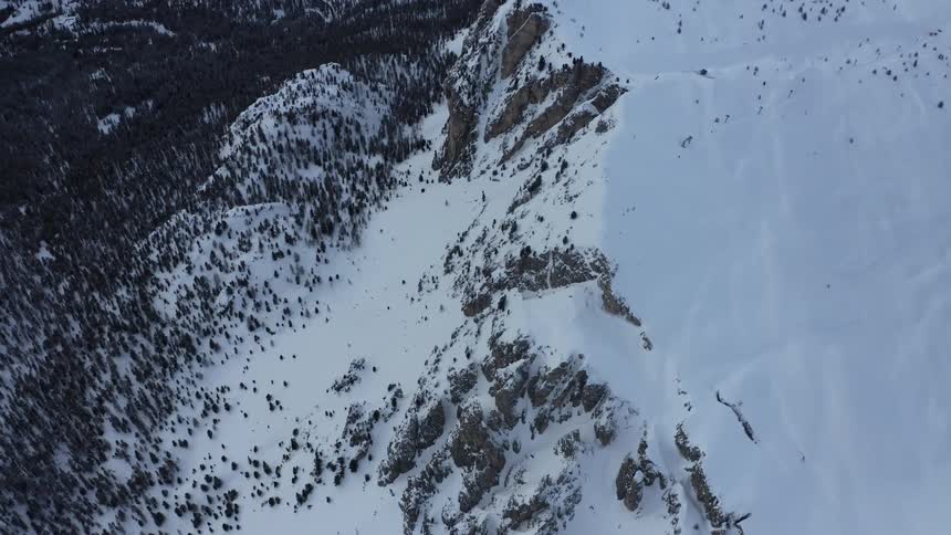 Snow covers mountain slope conifer forest and plateau