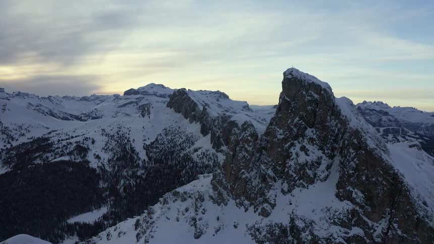 A mountain range covered in snow and ice with the sky and clouds in the background