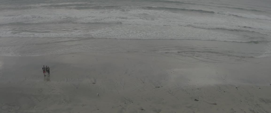 People are standing on a beach below on a cloudy day