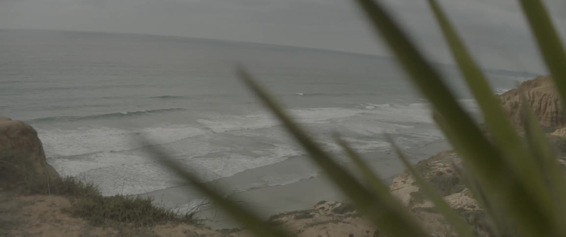 Waves roll onto a shore on a cloudy day