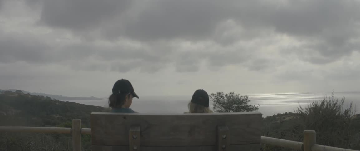 Two people on a bench on a cloudy day