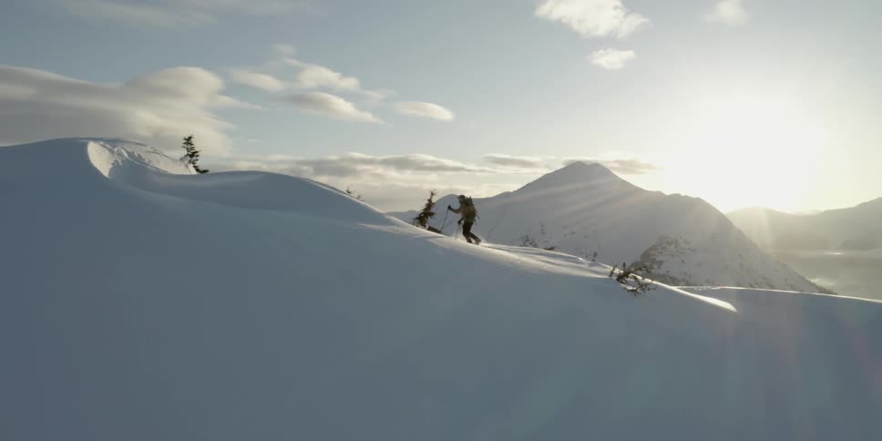 Someone is walking up a snow covered mountain with trekking poles
