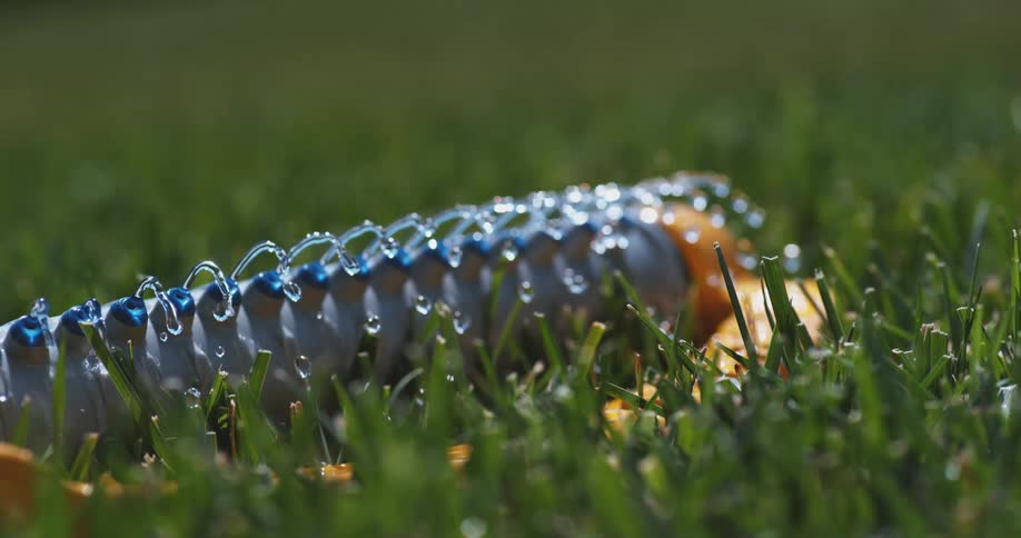 A sprinkler sprays drops of water on a lawn