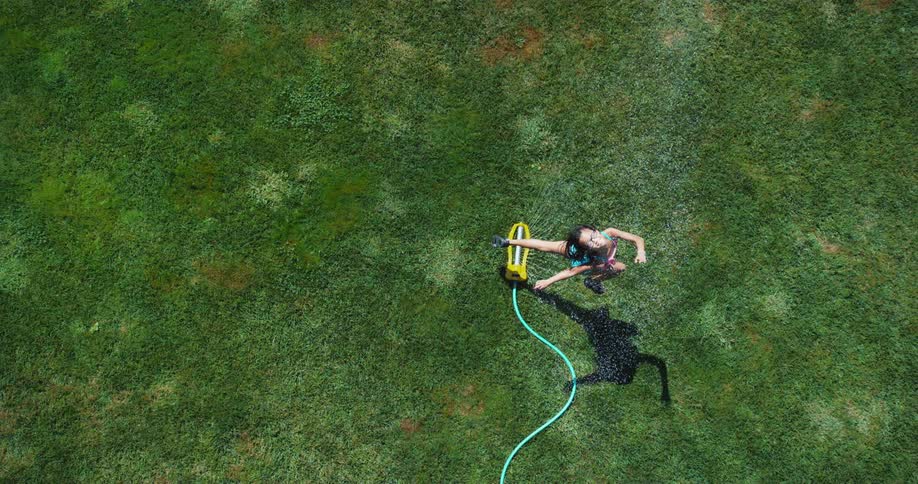 A child running through a sprinkler outdoors