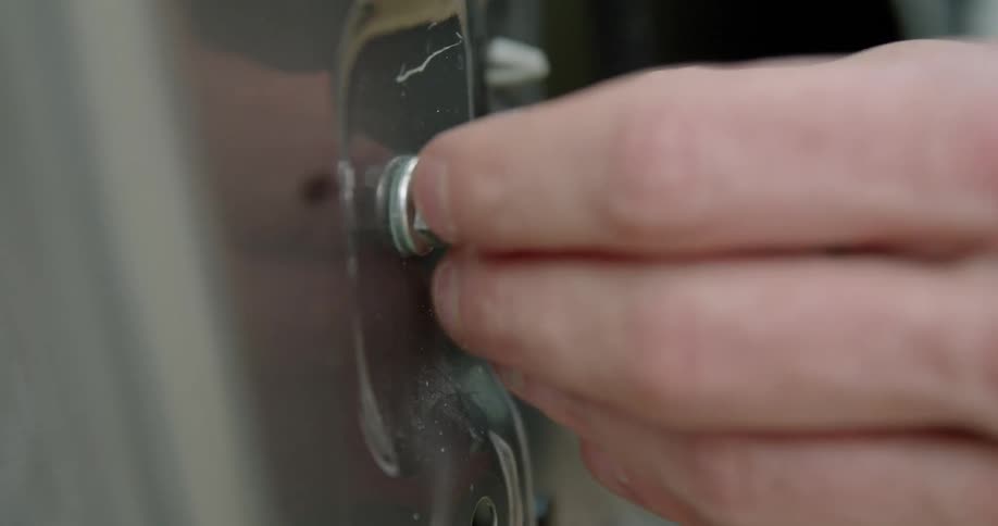 A person using a wrench to loose a bolt on the side of a machine