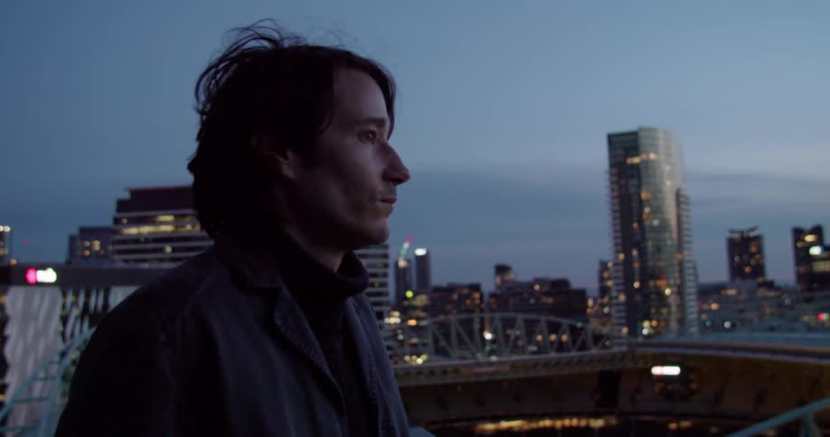 A man looks out over the city from the bridge