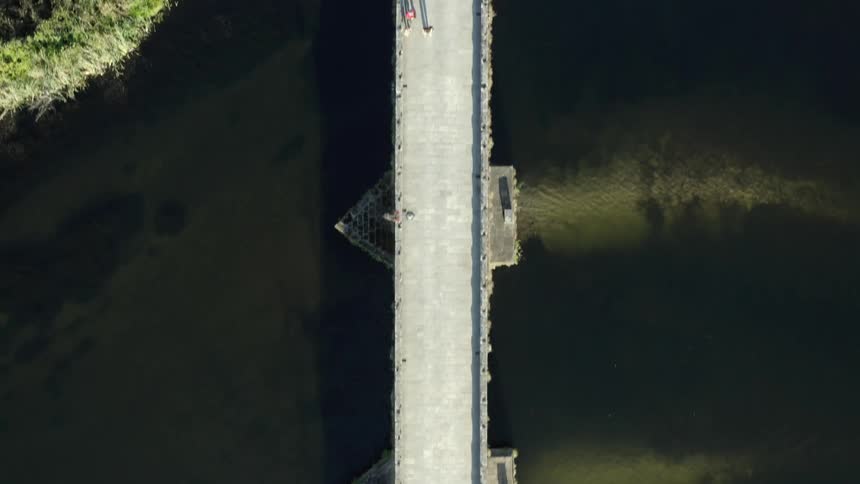 Aerial view of pedestrians walking on a bridge over a river inside a park