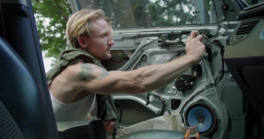 A man removes a panel cover from vehicle door and starts loosening a bolt with a ratchet