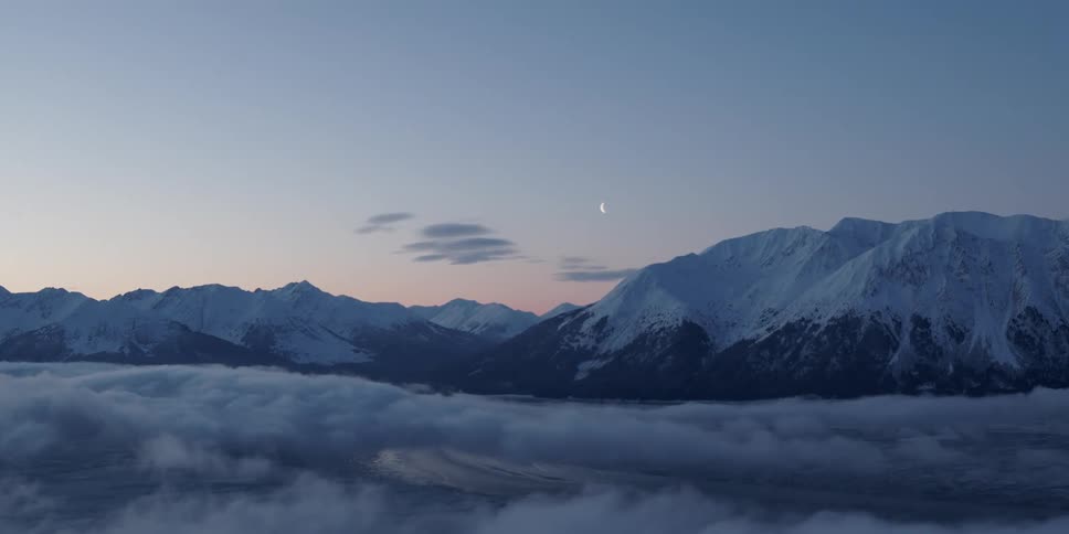 Aerial view of snow covered mountains is displayed at dusk