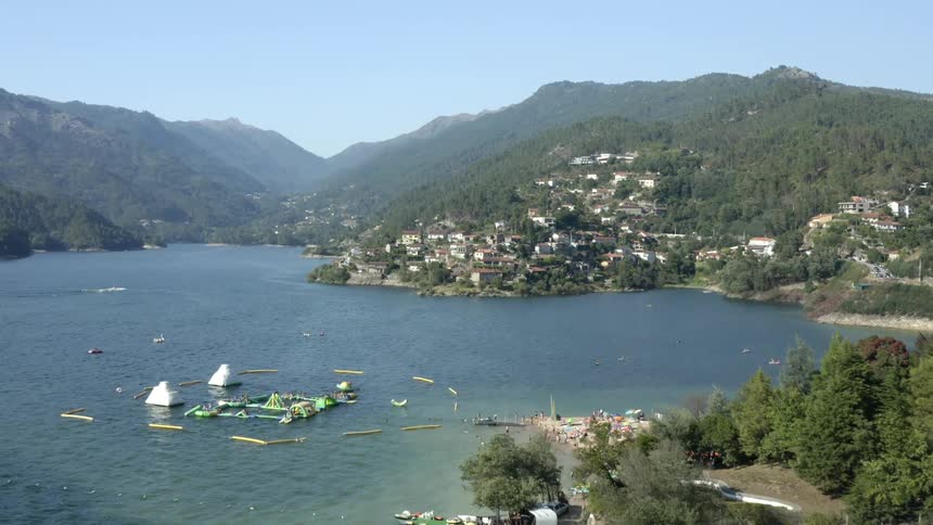 A coast with trees buildings and hills with the sky and clouds in the background