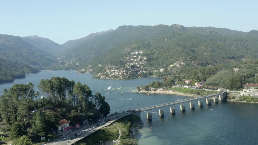 Cars travel across a bridge while motor boats pass underneath