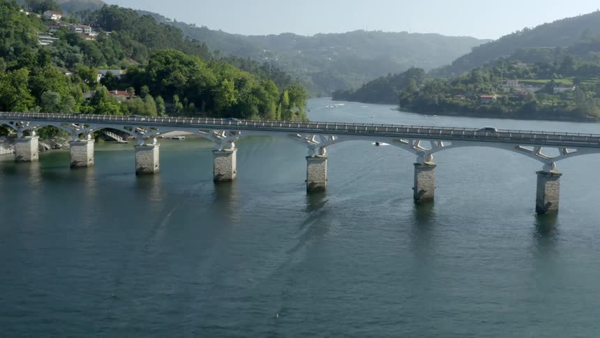 Aerial view of cars driving over two bridges and coastal town next to forest