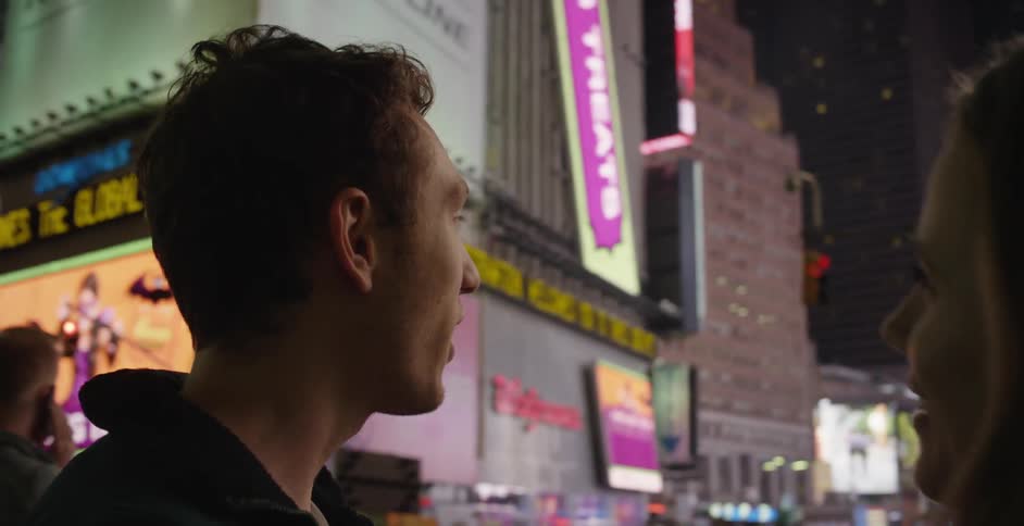 A man and woman talk in a city at night