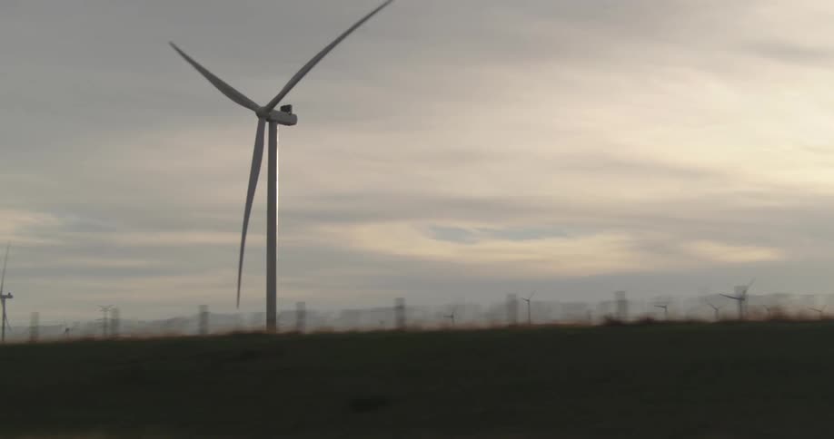 Wind turbines spin on a windfarm under a cloudy sky