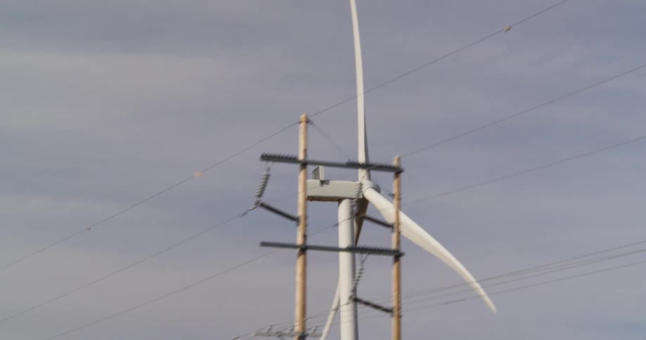 A wind turbine spins on a wind farm during the day