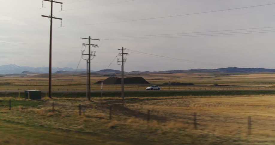 A car is driving through a rural area in the evening