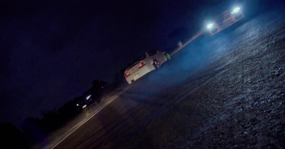 A vehicle drifting on a racetrack with trees the sky and clouds in the background