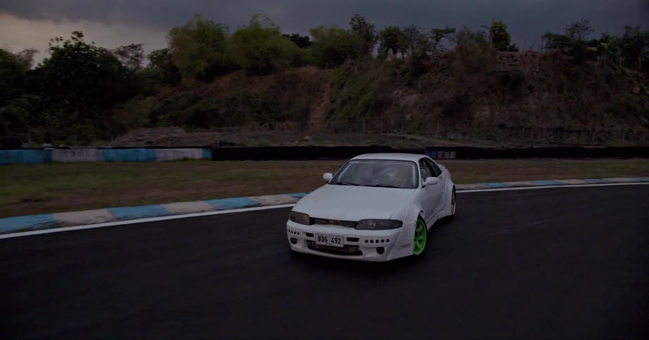 Aerial view of a white sports car drifting on a race track at evening