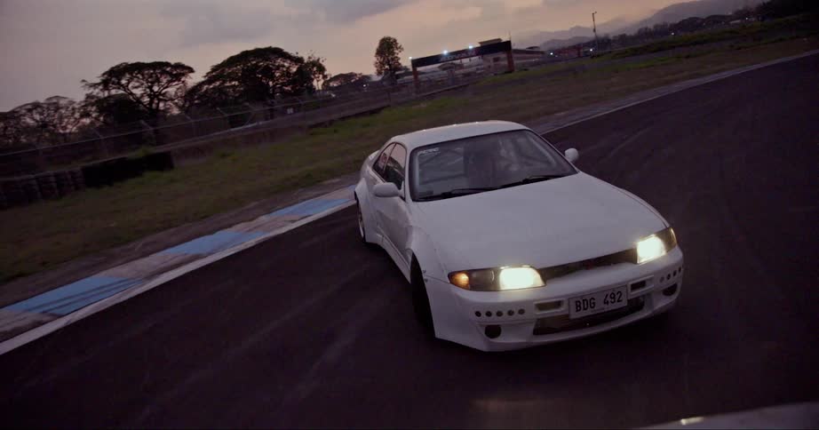 A race car drifts into the shoulder as it goes around a curve