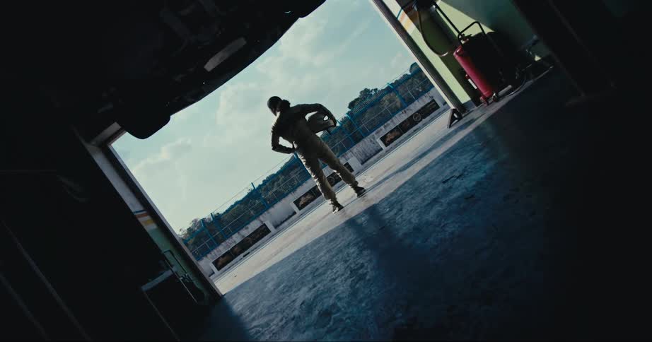 A race car driver looks across the track while standing in a garage