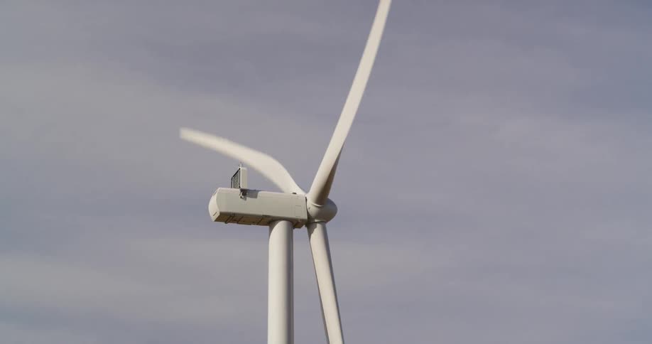 A wind turbine turning in the wind with the sky and clouds in the background