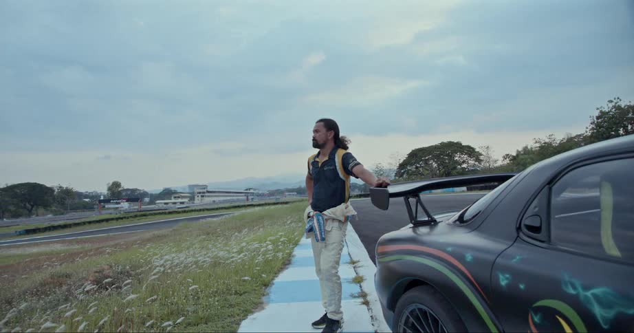 Portrait of a man standing next to an airbrushed sports car in a parking lot in a small rural town
