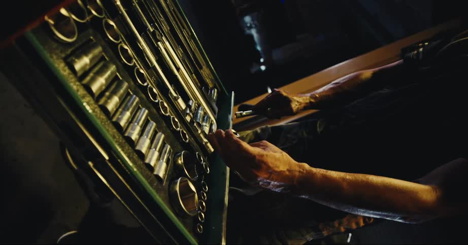 A mechanic opens the drawer of a standing tool chest and replaces sockets in their spot