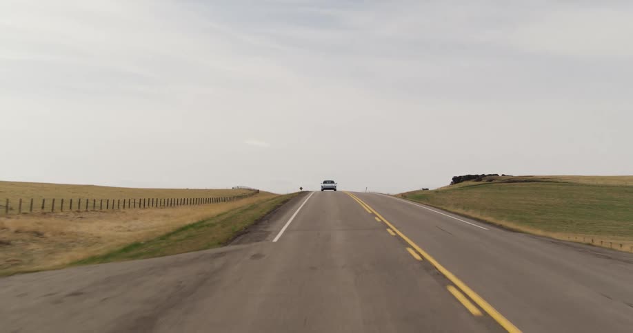 electric sports car drives downhill on asphalt road between fields