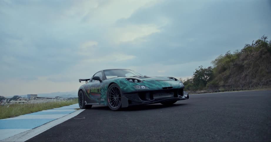 A graffitied race car sits parked at an angle on a race track