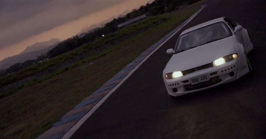 A car travels along a race track on a cloudy evening