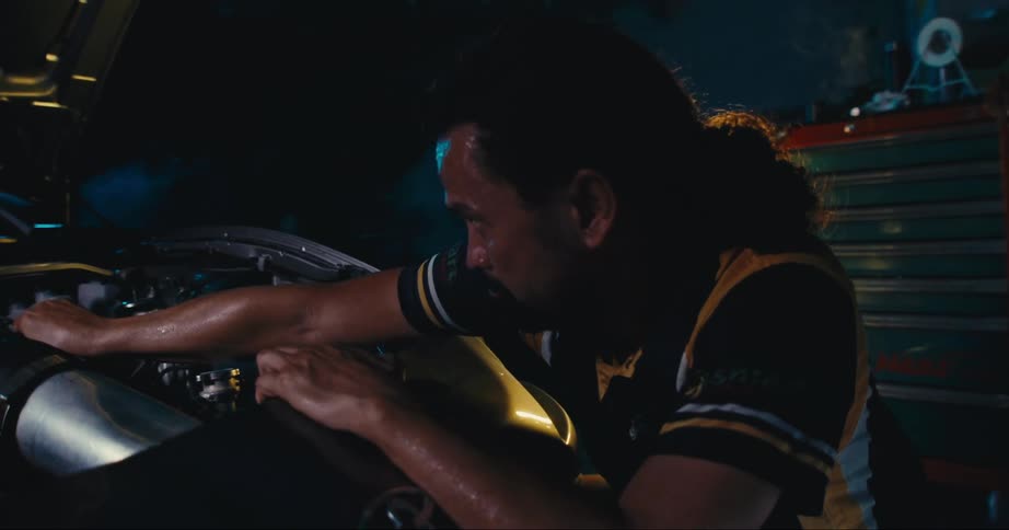 A man is in a garage and working on a car